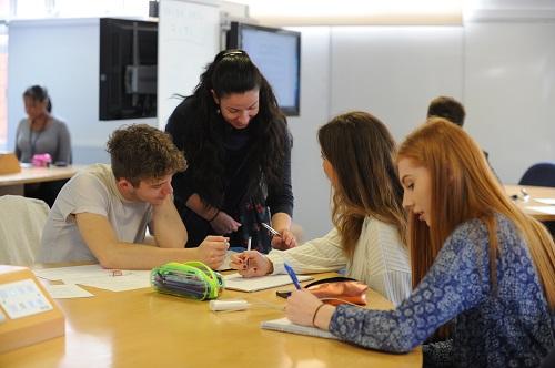 Three students working together in a workshop, supported by a tutor